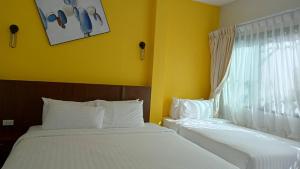 two beds in a room with yellow walls and a window at Blue Orchid Beach Krabi - SHA Certified in Ao Nam Mao