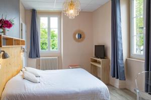 a bedroom with a white bed and a chandelier at Hostellerie du Parc in Cambo-les-Bains