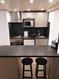 uma cozinha com um balcão e dois bancos de bar em Superbe appartement neuf T3 6pers 45m2 em Font Romeu Odeillo Via