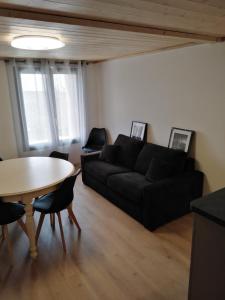 a living room with a black couch and a table at Superbe appartement neuf T3 6pers 45m2 in Font-Romeu-Odeillo-Via