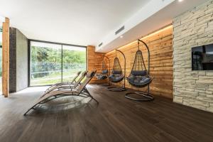 a group of chairs in a room with a stone wall at Gaia Residence Hotel in Mezzana