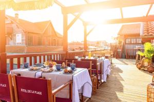 a dining room with tables and chairs on a deck at Hotel de La Plage in Contis-les-Bains