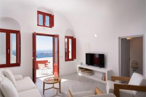 a living room with white furniture and a view of the ocean at Serendipity Cliffside Villa & Suites in Imerovigli