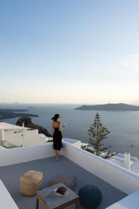 a woman standing on a balcony looking out over the ocean at Serendipity Cliffside Villa & Suites in Imerovigli