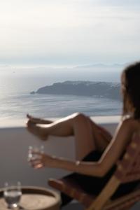 a woman sitting in a chair with a glass of wine at Serendipity Cliffside Villa & Suites in Imerovigli