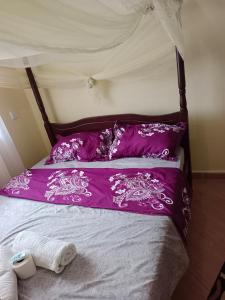 a bed with a purple comforter and pillows at Hossanah Furnished one bedroom in Kasarani,Nairobi in Nairobi