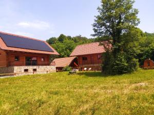une grange avec une maison et un arbre dans un champ dans l'établissement Brunarica Biopark -Log house Biopark, à Grosuplje