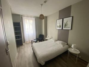 a bedroom with a bed and a table and a chair at Le Relais de la Gare in Dole