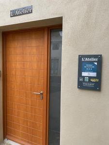 una puerta de madera a un edificio con un cartel en L'atelier, en Capestang