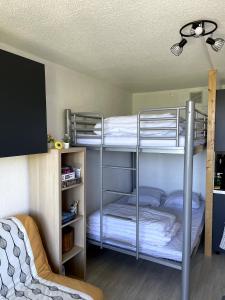 two bunk beds in a room with a tv at Studio au pied des pistes avec balcon 4/6 pers in Villarembert