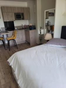 1 dormitorio con 1 cama blanca y cocina en CHANGÉ, 10mn LE MANS 72 en Changé