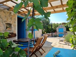 un patio con mesa y sillas bajo una pérgola de madera en Robinson house Ruža, en Neviđane