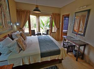 a bedroom with a bed and a table and a mirror at Crocodile Kruger Safari Lodge in Marloth Park