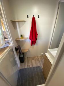 a bathroom with a red coat hanging on a wall at Mobil home de charme in Fréjus