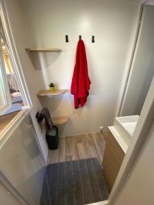 La salle de bains est pourvue d'un manteau rouge accroché au mur. dans l'établissement Mobil home de charme, à Fréjus