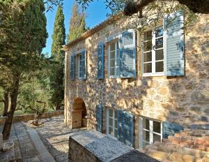 an old stone house with blue shutters and trees at Patrick & Joan Leigh Fermor House in Kardamyli