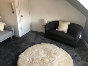 uma sala de estar com um sofá preto e um tapete branco em Flat 8 Buxton Town centre apartment em Buxton