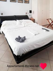 ein großes Bett mit schwarzem Rahmen und weißer Bettwäsche in der Unterkunft Appartamento Merano nel cuore in Meran