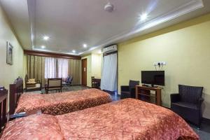 a hotel room with two beds and a flat screen tv at KRISHNA HERITAGE RESORT in Badami