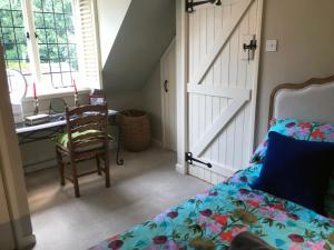 a bedroom with a bed and a desk and a door at Hornes Cottage in Longborough
