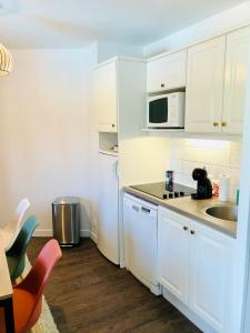 a white kitchen with a sink and a microwave at Bel appartement cosy en résidence avec piscine in Deauville