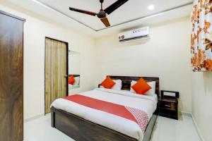 ein Schlafzimmer mit einem großen Bett mit orangefarbenen Kissen in der Unterkunft Hotel Blue Leaf in Rajkot