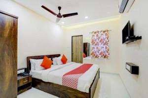 Hotel Blue Leaf في راجكوت: غرفة نوم بسرير وتلفزيون في غرفة