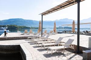 a group of chairs and umbrellas next to a body of water at Apart-hotel Villa Lav in Tivat
