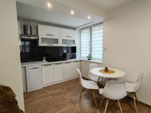 una cucina con mobili bianchi, tavolo e sedie di Apartament 20tka a Szczawnica