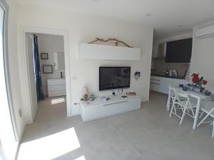 a white living room with a television and a table at Mirasole Holiday House in Leggiuno