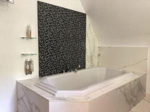 eine weiße Badewanne im Bad mit einer schwarzen Wand in der Unterkunft La Forge De La Coudraie in Pleugueneuc