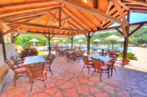 a patio with tables and chairs and a pool at Mermaid Pool Studios and Bar in Paleokastritsa