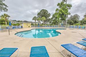 a swimming pool with blue chairs in a resort at Sunny Myrtlewood Condo with Golf and Pool Near Beach! in Myrtle Beach