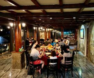 a group of people sitting at a table in a restaurant at DONG VAN CLIFFSIDE HOUSE in Dồng Văn