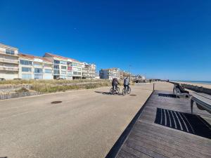 - 2 personnes à vélo sur une route à côté de la plage dans l'établissement Grand studio cabine 4 pers, balcon, rénové, proche océan, Saint-Hilaire-de-Riez - FR-1-224C-160, à Saint-Hilaire-de-Riez