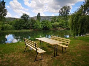 dos bancos sentados junto a una mesa de picnic frente a un lago en Villa Denis en Mostar