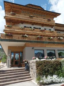 - un bâtiment avec des escaliers et des fleurs devant dans l'établissement Hotel Colfosco, à San Martino di Castrozza