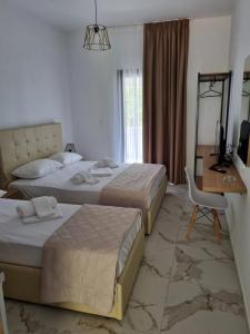 um quarto de hotel com duas camas e uma secretária e uma televisão em MANGO Skiathos em Skiathos