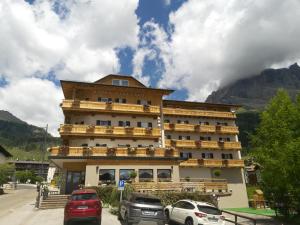 a large hotel with cars parked in front of it at Hotel Colfosco in San Martino di Castrozza
