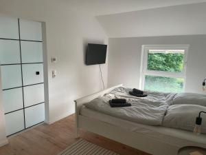 a white bedroom with a bed and a window at Klein Westerland OG in Brodersby