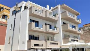 a white building with balconies and an umbrella at fronte mare in Pozzallo +9 photos