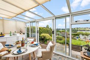 a conservatory with a table and chairs and glass doors at Curlew Cottage - Character Cottage with Superb River Views in Dittisham