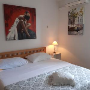 a bedroom with a white bed with a painting on the wall at Apartment Vanda in Splitska