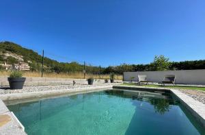 a swimming pool with blue water in a yard at Toupie et Bicyclette in Charmes-sur-Rhône