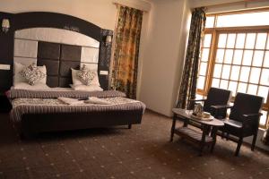 a bedroom with a bed and a table and chairs at Hotel Al Azrah in Srinagar