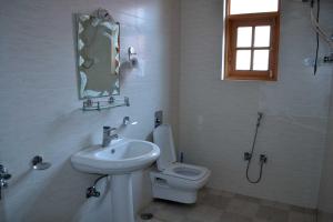 a white bathroom with a toilet and a sink at Hotel Al Azrah in Srinagar