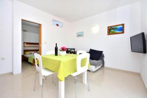 a dining room with a green table and white chairs at Apartments Dida in Hvar