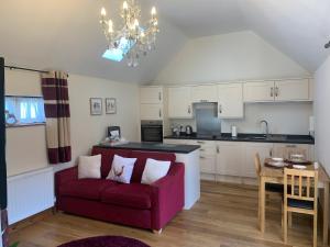 sala de estar con sofá rojo y cocina en Meals Farm Holiday Cottages - The Stables en North Somercotes
