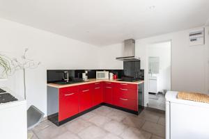 een keuken met rode kasten en een witte muur bij Le Rethel in Caen