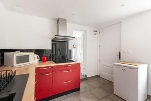 een keuken met rode kasten en een magnetron bij Le Rethel in Caen